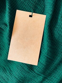 Blank fashion label tag, sale price card on luxury fabric background, shopping and retail concept