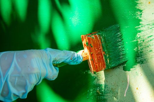 a man's hand paints a wall.