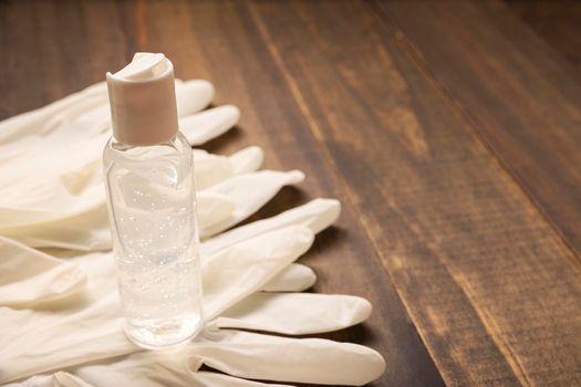 medical latex gloves and hand sanitizer gel bottle for protection on wooden background. Useful for pandemic prevention concept