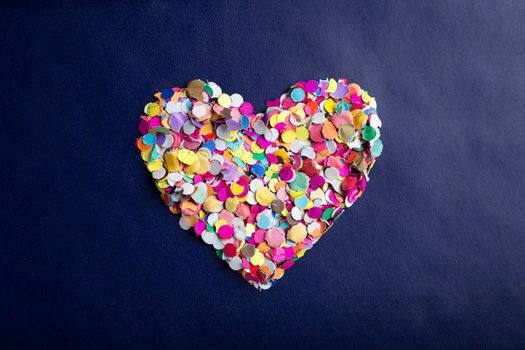 love concept image of heart shape made of colorful confetti on blue paper texture background