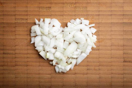 love concept image of heart shape made of diced onion on bamboo cutting board background