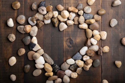 love concept image of heart shape frame made of round pebbles on wooden background