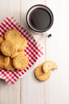 Top view image of Homemade crunchy cookies and a black coffee cup on white wooden rustic table. Flat Lay