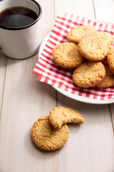 Homemade crunchy cookies and a coffee cup on white wooden rustic table