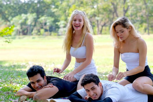 Two lovely teens massage to sport men in the garden with fun emotion.