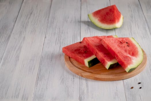 Close-up of sliced pieces of ripe red watermelon on a light wooden surface. Healthy food concept, summer food. Selective focus.