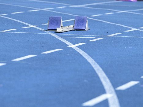 Starting blocks ready on blue running tracks lanes at track and field stadium. Sport accessory.