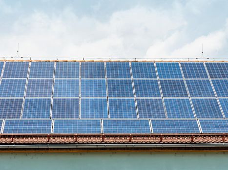 Roof with solar panel reflecting the sun light in the perfect sky with fluffy white clouds 