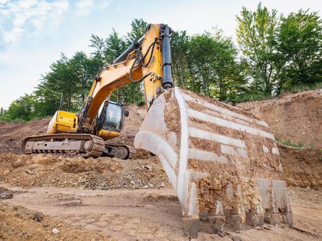 Track type loader is mining stones in opencast mining quarry. Heavy machinery in the open pit, excavators, dozers and trucks. Digging and excavation operations