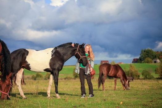 Piebald mare with a girl on meadow