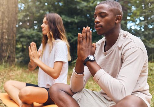 Yoga, man and woman in prayer hand pose together in nature, grass and outdoors. Zen, meditation and athletic friends doing pilates outside on the ground or field for health, fitness and wellness