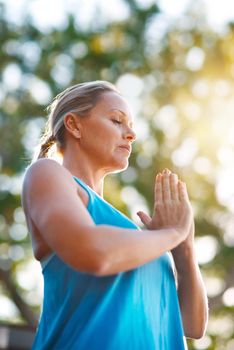 Im surrounded by peace and beauty all around. Low angle shot of a mature woman meditating outdoors