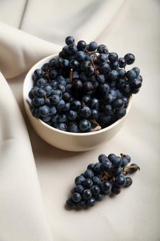 Apetizing fresh grapes in bowl on white background