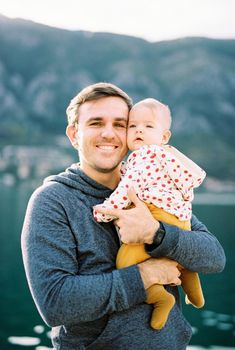 Smiling dad hugs the baby in his arms. Portrait. High quality photo