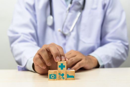 Hand holding wooden cubes block with insurance health car medical symbol on background and copy space.