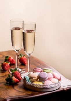 champagne and macarons with strawberries on a wooden table