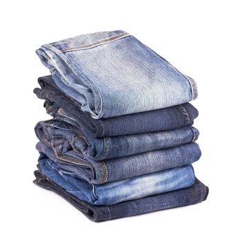 Stack of blue jeans on a white background.