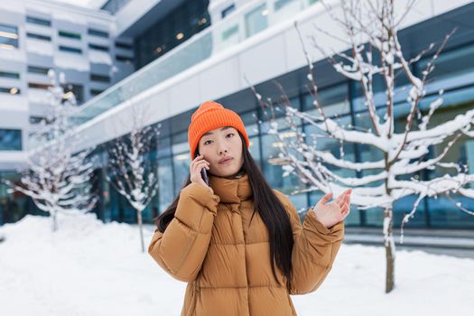 Excited happy Korean woman talking by mobile phone and laughing, she heard good news. Portrait of cheerful asian hipster holding smartphone