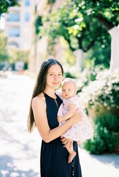 Mom with a little baby girl in her arms stands on the street. High quality photo