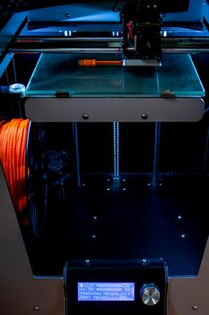 printing on a 3d printer. orange trident is printed with plastic on a 3d printer