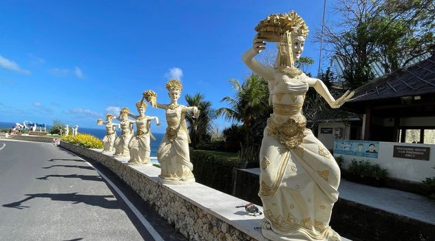 Bali, Indonesia - 06 July 2022: Sculpture of Balinese dancers at the entrance to Pantai Melasti Beach under the blue sky