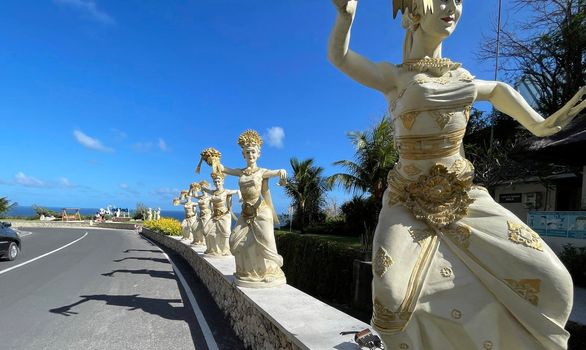 Bali, Indonesia - 06 July 2022: Sculpture of Balinese dancers at the entrance to Pantai Melasti Beach under the blue sky