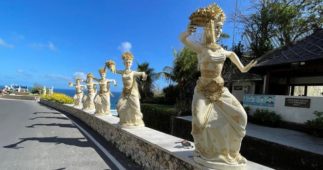 Bali, Indonesia - 06 July 2022: Sculpture of Balinese dancers at the entrance to Pantai Melasti Beach under the blue sky