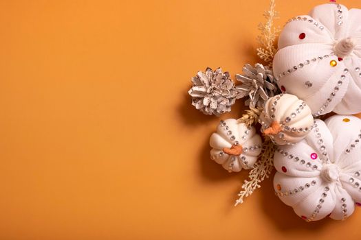 White decorative hand made pumpkins with shiny stones and pine cones on colored background top view. Thanksgiving day concept