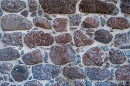 Fragment of the wall of an ancient medieval defensive fortress made of natural stone.