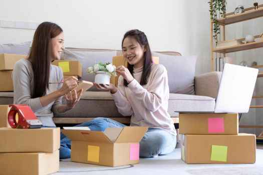 Portrait of Starting small businesses SME owners, two Asian woman check online orders Selling products working with boxs freelance work at home office, sme business online small medium enterprise.