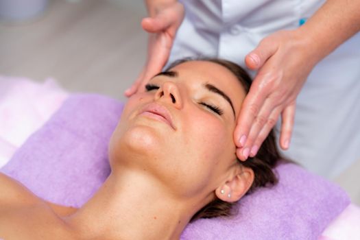 Relaxing massage. European woman getting facial massage in spa salon, side view.