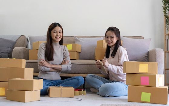 Portrait of Starting small businesses SME owners, two Asian woman check online orders Selling products working with boxs freelance work at home office, sme business online small medium enterprise.