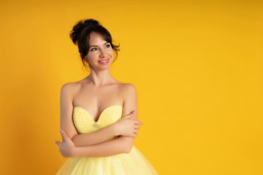 Smiling beautiful middle-aged woman on a yellow background in the studio