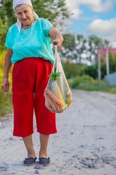Grandmother carries vegetables in a shopping bag. Selective focus. Food.
