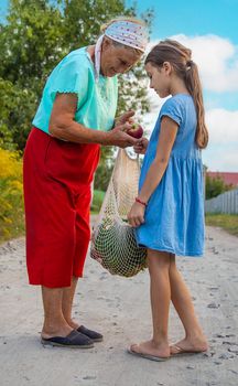 Child and grandmother carry vegetables in a bag. Selective focus. Food.