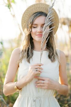 Dry branch of reed in the hands of a girl in a straw hat. Portrait. High quality photo