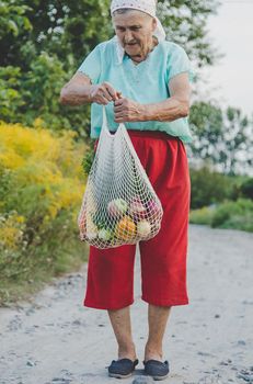 Grandmother carries vegetables in a shopping bag. Selective focus. Food.