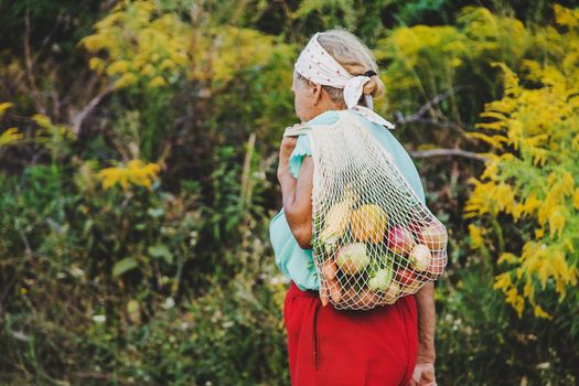 Grandmother carries vegetables in a shopping bag. Selective focus. Food.