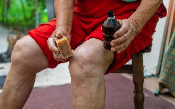 Grandmother treats her knees with soap. Selective focus. Woman.