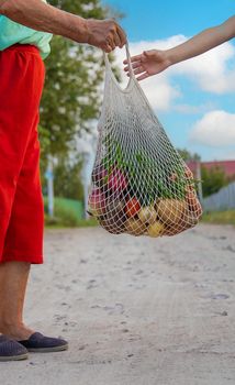 Child and grandmother carry vegetables in a bag. Selective focus. Food.