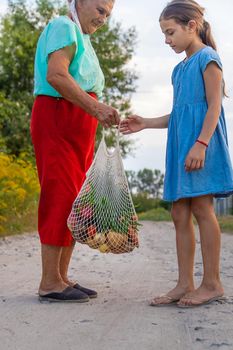 Child and grandmother carry vegetables in a bag. Selective focus. Food.