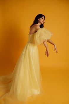 Portrait of a beautiful middle-aged woman in a yellow dress, her hair pulled up against a yellow background.