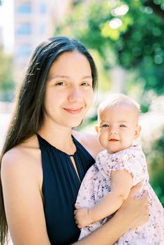 Smiling mom with a little baby girl in her arms. High quality photo