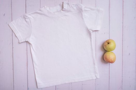 White children's t-shirt mockup for logo, text or design on wooden background top view.