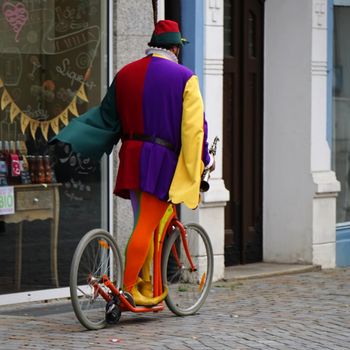 Hamelin, Germany - July 16 2017 The Pied Piper of Hamelin, dressed in multicolored clothes, rides a scooter with a clarinet in his hand through Hamelin for the tourists