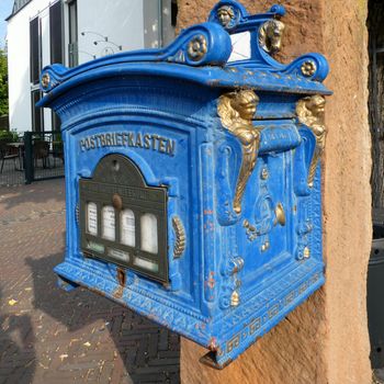 Neuenhaus, Germany - Aug 15 2022 Antique blue German mailbox from  the 19th century. It is still in use.