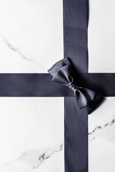 Holiday gift, decoration and sale promotion concept - Black silk ribbon and bow on marble background, flatlay