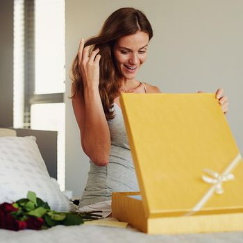 Romantic gestures make all the difference. a young woman opening a surprise gift at home