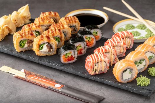 Sushi set of various products on a black stone plate. Blur background and selective focus