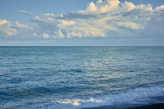 Sea shore with pebbles, wet sea pebbles on the beach and quiet sea surf. Restless sea and waves.